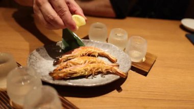 Izgara karidese limon sıkan kişi.