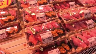 Süpermarketin rafında çeşitli suşi paketleri.