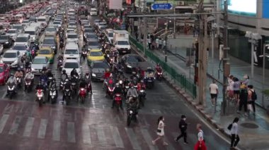 Motosikletler ve arabalar kalabalık bir kavşakta yol alırlar.