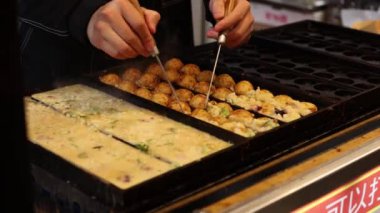 Eller ızgarada takoyaki çeviriyor.