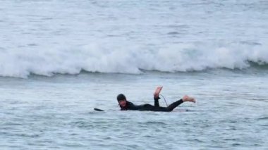 Sörfçü okyanusta kürek çekiyor ve dalgaları yakalıyor
