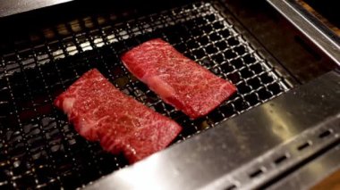 Biftek parçaları tel askıda ızgara yapıyor.