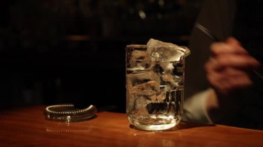 Barmen barda bir bardağa buz ekliyor.