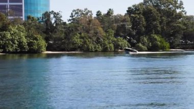 Bir sürat teknesi manzaralı bir kanal boyunca seyahat eder.