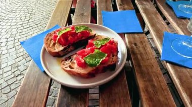 Masadaki fesleğenli bruschetta 'ya uzanan el.