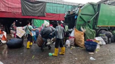 İşçiler kalabalık bir pazarda çöpleri temizliyor