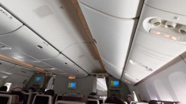 Oturan yolcular, uçuş eğlencesi ekranları görünür.