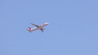 Açık mavi gökyüzüne karşı uçmakta olan uçak