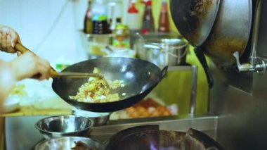 Şef bir tavada ustalıkla yemek hazırlar.