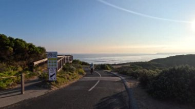 Manzaralı sahil yolunda bisiklet süren bir bisikletçi.