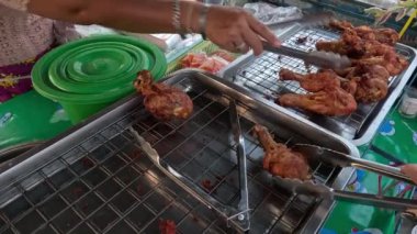 Satıcı müşterilere kızarmış tavuk hazırlar ve satar..