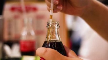 Eller kola şişesine saman koyuyor.