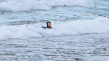 Genç çocuk sörf yapıyor ve dalgalar halinde düşüyor