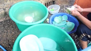 İki kişi birlikte dışarıda bulaşık yıkıyor.