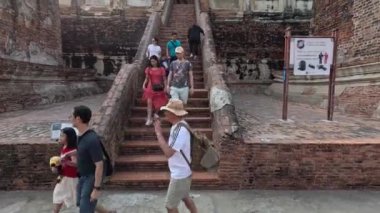 Turistler tarihi bir tapınağın merdivenlerinden çıkıyorlar.