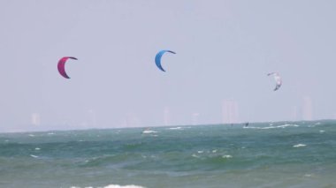 Uçurtma sörfçüleri dalgalı okyanus dalgalarında süzülür