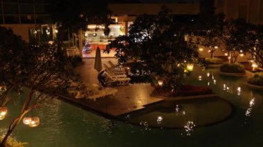 Gece vakti havuz kenarında yanan bir bahçe manzarası