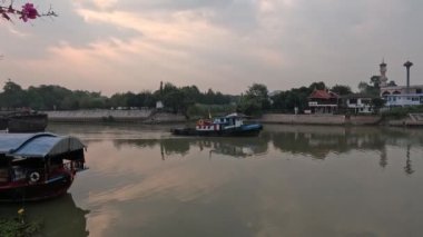 Gün batımında sakin bir nehirde süzülen tekneler