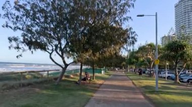 İnsanlar kıyı parkında güneşli bir günün tadını çıkarıyorlar.