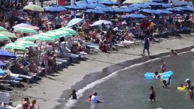 İnsanlar kumsalda güneşli bir günün tadını çıkarıyor.