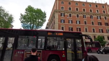 Otobüs caddeyi geçerken insanlar bekliyor.