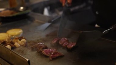 Aşçı ustalıkla ızgarada biftek hazırlar.