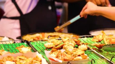 Satıcılar Bangkok pazarında deniz ürünleri krepleri hazırlıyorlar.