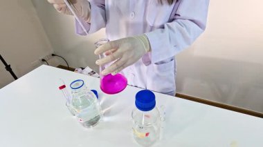 Bir bilim adamı bir laboratuvar ortamında potasyum permanganat azaltma deneyi yürütüyor.