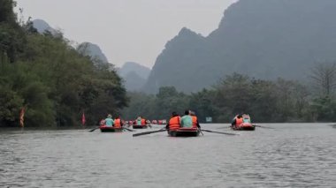 Turistler manzaralı bir nehirde kürek çekiyorlar.