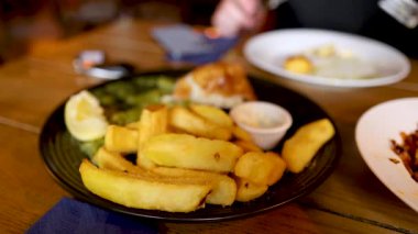 Masada balık ve patates yiyen insanlar.