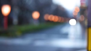 Alacakaranlıkta bir cadde boyunca odak dışı ışıklar