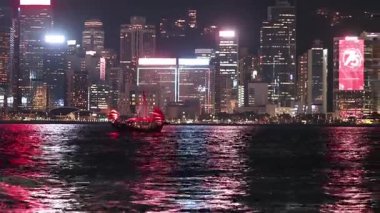 Bir tekne aydınlatılmış şehrin ufuk çizgisinden geçiyor.