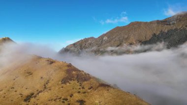 Queenstown dağlarının hava manzarası, gün doğumunda açık mavi gökyüzü ve altın ışıkla kaplanmış.