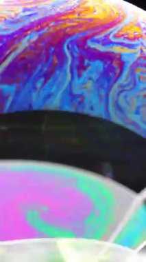 Bir sabun kabarcığı yüzeyinde hareketli renkler, dinamik ışıklandırma ve pürüzsüz kamera hareketiyle yakın planda yakalanır.