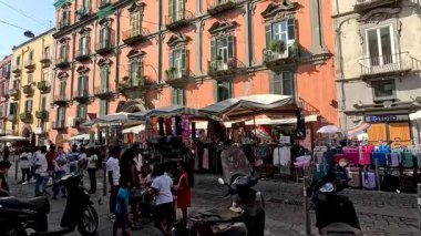 İnsanlar hareketli bir sokak pazarından alışveriş yapıyorlar.