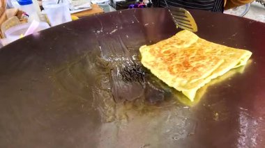 Bir sokak satıcısı Tayland, Kanchanaburi 'de ızgarada kızartılmış roti pişiriyor. Süreçte geleneksel teknikler ve canlı sokak yemekleri kültürü vurgulanıyor