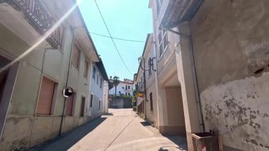 Güneş ışığı ve binalarla dolu sessiz bir ara sokak.