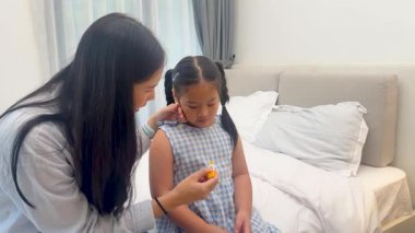 Bir anne, kendini iyi hissetmeyen kızıyla yumuşak bir odada ilgilenir. Rahatlık sunar ve ateşini ölçer.