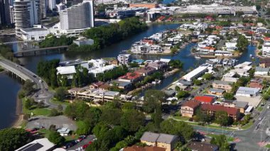 Hava görüntüleri, Gold Coast 'un su yolları, yerleşim alanları ve parlak gün ışığı altındaki yüksek binalarla çevrili kentsel ortamını gösteriyor.