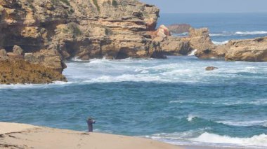 Kaya kıyısı dalgalarında balık tutan insanlar