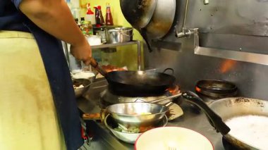 Şef, yoğun bir mutfakta yemek hazırlıyor.