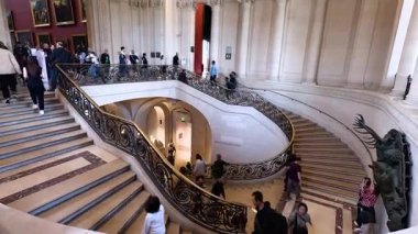 Louvre Müzesi 'ndeki süslü merdivenlerde yürüyen insanlar.