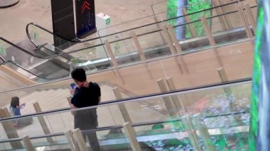 Sessiz bir alışveriş merkezinde yürüyen merdivenden inen kişi.