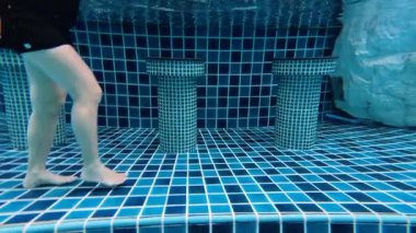 Yüzme havuzunda su altında yürüyen biri.