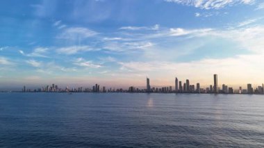 Altın Sahilinin ufuk çizgisinde gün doğumunu yakalayan hava zaman döngüsü canlı renkleri ve sakin okyanus manzaralarını vurguluyor.