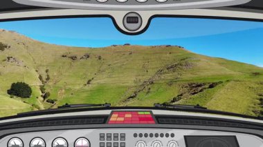 Uçan bir kokpit manzarası canlandırması, açık mavi gökyüzünün altındaki yeşil tepeler