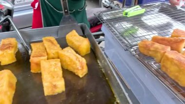 Bir satıcı, Kanchanaburi, Tayland 'da bir sokak tezgahında tereyağlı ekmek kızartıyor. Sahne canlı sokak yemekleri kültürünü yakalıyor.