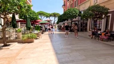 İnsanlar güneşli bir sokakta yürüyor