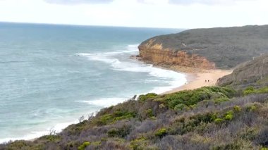 Büyük Okyanus Yolu, Avustralya boyunca kayalıkları ve yumuşak gün ışığı altında okyanus dalgaları ile sakin bir kıyı manzarası.
