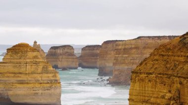 Avustralya 'daki Büyük Okyanus Yolu boyunca çekilen 12 havarinin bulutlu gökyüzü altındaki kaya oluşumlarının huzurlu bir görüntüsü.